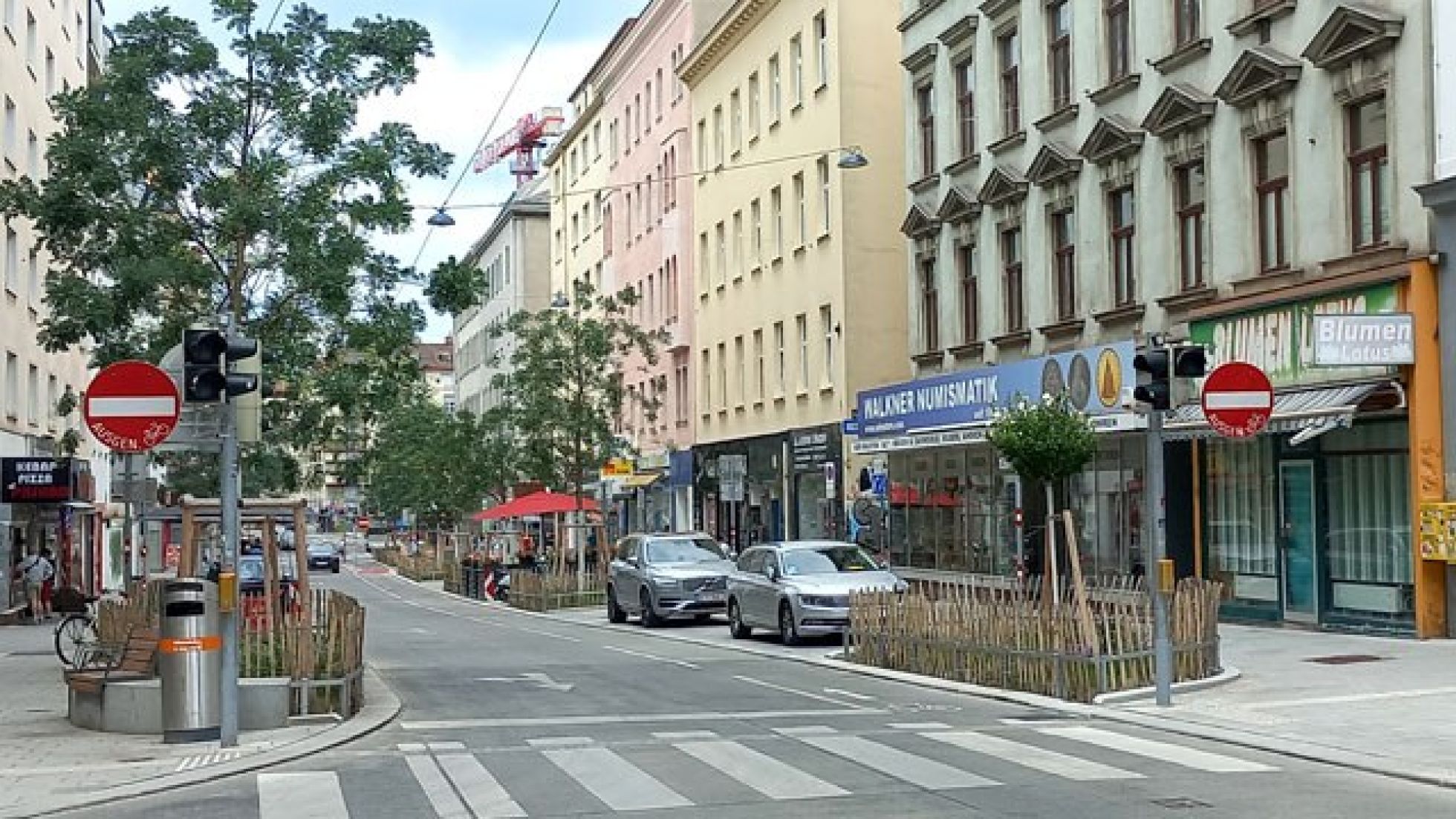 Eine Straße ist links und rechts mit Verkehrsschildern "Einfahrt verboten ausgenommen Radfahrer" gekennzeichnet. Auf der Fahrbahn ist ein Mehrzweckstreifen zum Radfahren gegen die Einbahn eingezeichnet.