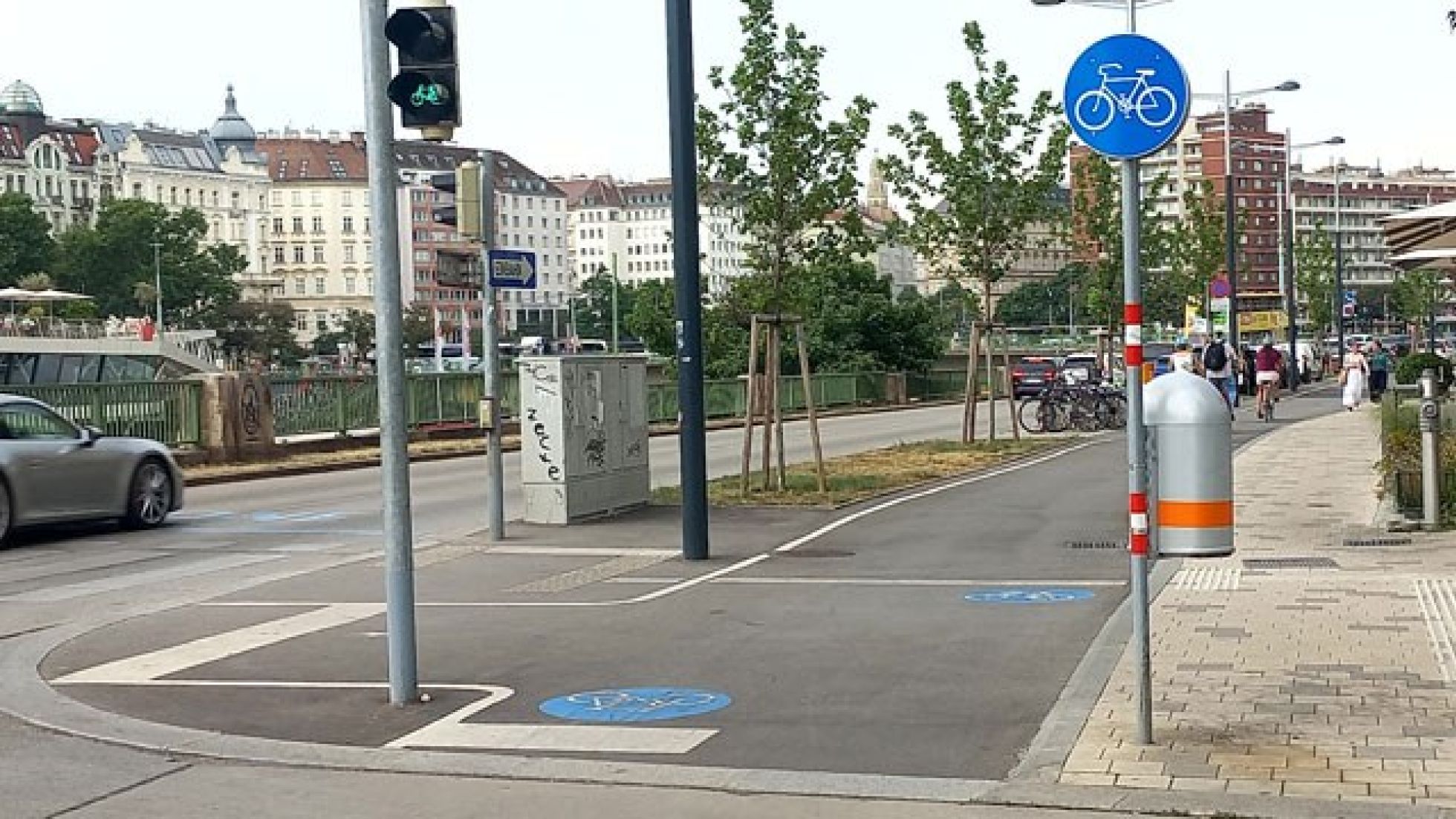 copyright: MA 46 Radweg an einer Kreuzung. Der Radweg ist mit Verkehrszeichen und Piktogrammen am Boden gekennzeichnet und hat eine Fahrradampel, die grün anzeigt.