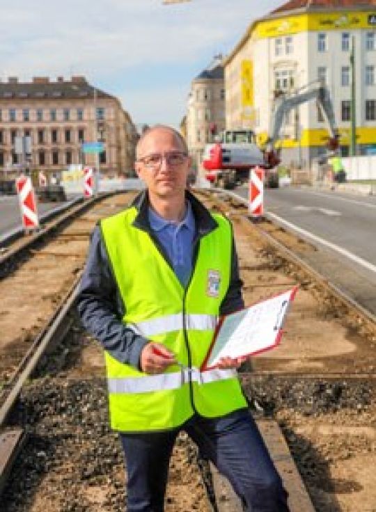 Mann in Schutzweste vor einer Gleisbaustelle