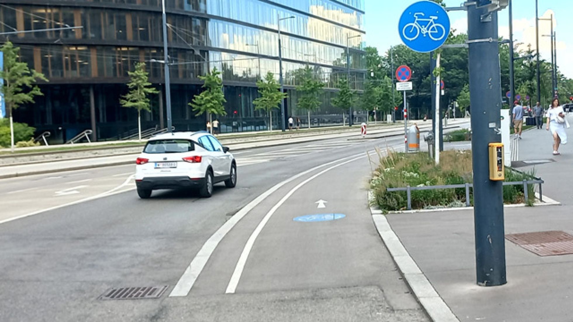 copyright: MA 46 Ein Radweg verläuft zwischen Gehsteig und mehrspuriger Fahrbahn. Der Radweg ist mit einem Verkehrszeichen und einem Piktogramm mit Richtungspfeil am Boden gekennzeichnet.