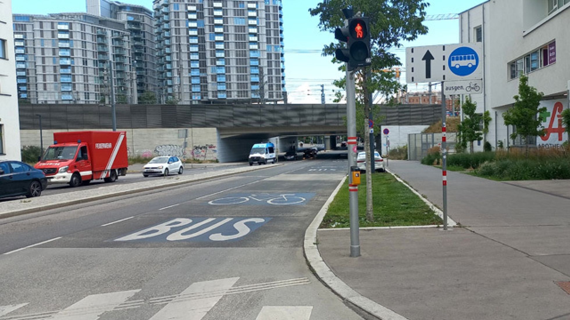 Auf einer 2-spurigen Fahrbahn ist der rechte Fahrstreifen mit der Aufschrift "Bus" und einem großen Fahrrad-Piktogramm gekennzeichnet. Ein Verkehrsschild weist auf die Busspur hin.
