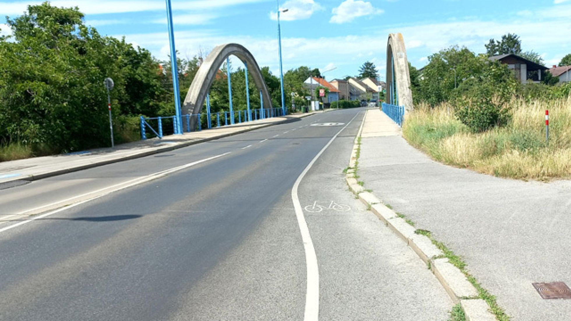 copyright: MA 46 Auf der Fahrbahn ist vor einer Brücke ein Radfahrstreifen mit Radpiktogramm markiert. Der Radfahrstreifen ist von der restlichen Fahrbahn durch eine Trennlinie abgetrennt.