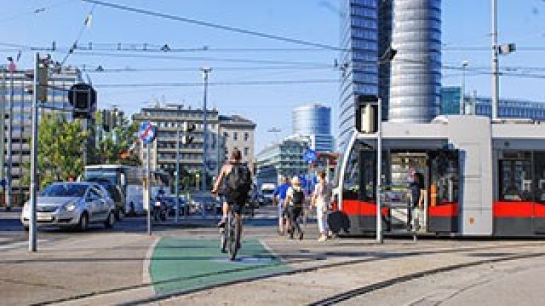 Verkehrsteilnehmerinnen und Verkehrsteilnehmer auf einer Wiener Straßenkreuzung
