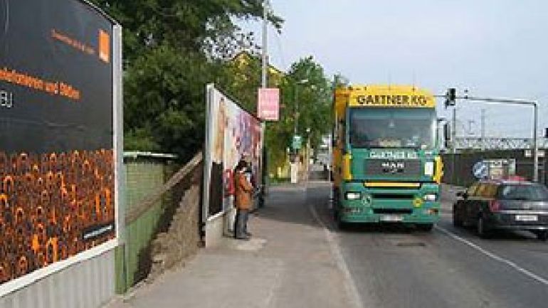 Bushaltestelle Hafenzufahrtstraße (stadtauswärts): Plakatwand, Frau auf schmalem Gehsteig, Lkw