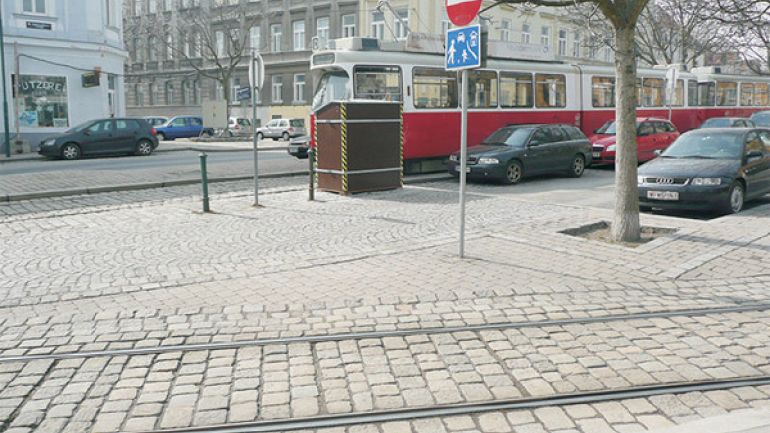 copyright: AUVA Endstation der Straßenbahnlinie D: Breiter Bereich ohne Zebrastreifen mit Straßenbahnschienen, Fußgängerinseln und Straßen mit parkenden Autos