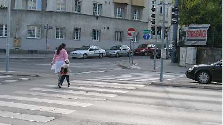 Kreuzungsbereich Triester Straße - Windtenstraße: Mutter und Kind auf Zebrastreifen, Auto hält an