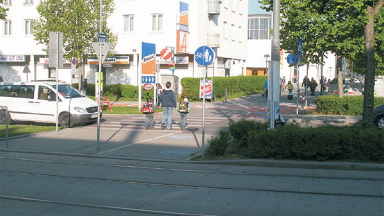 Kreuzungsbereich Otto-Probst-Straße - Tesarekplatz: Frau mit Kindern überquert den Zebrastreifen über die Autofahrbahn