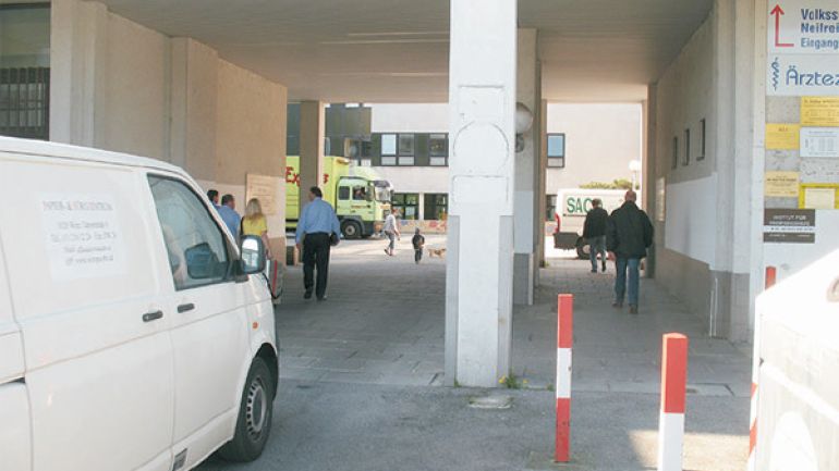 copyright: AUVA Bereich Karl-Wrba-Hof: Durchlass unter einem Wohnhaus mit einem Weg für Autos und einem baulich abgegrenzten schmalen Durchgang für Fußgänger