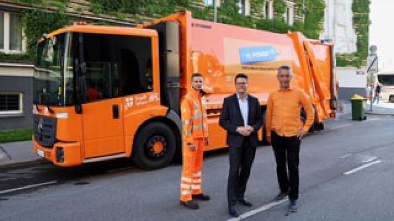 copyright: PID/Votava 3 Personen stehen vor dem orangen Wasserstoff-Müllauto