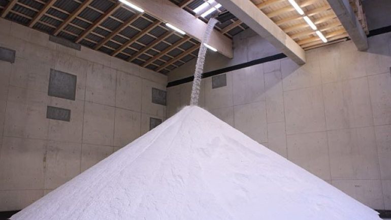 Salz fällt von Förderband auf Salzberg