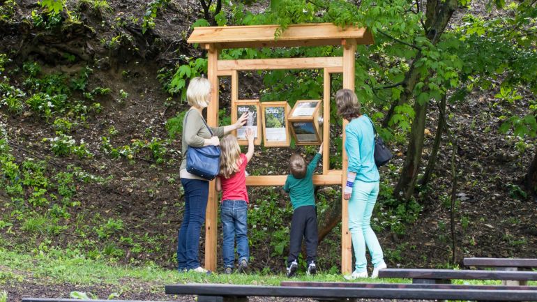 2 Erwachsene und 2 Kinder an einer interaktiven Schautafel