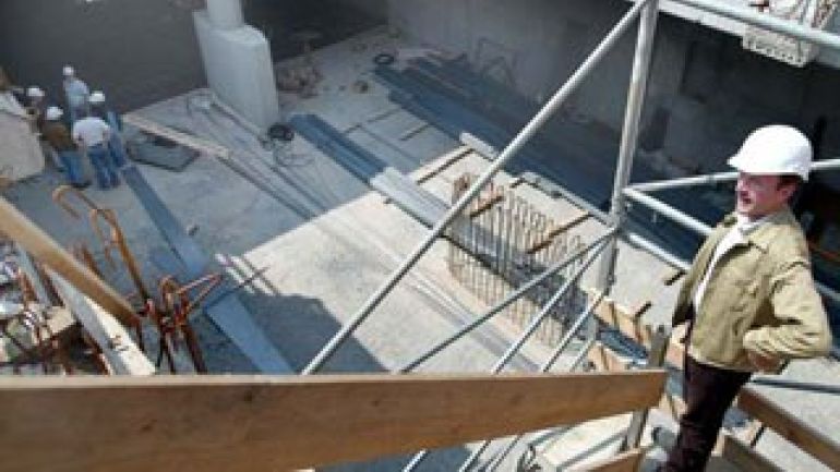 Keller im Rohbau auf einer Baustelle; Mann mit Bauhelm