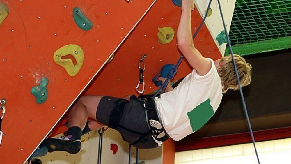 copyright: Eva Kelety Ein Junge hängt am Seil an einer Indoor-Kletterwand