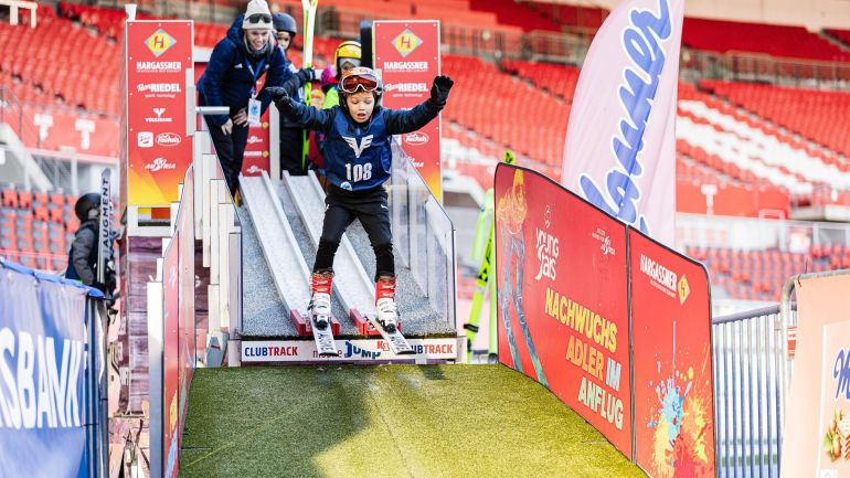 Kind springt im Stadion auf einer Kinder-Schanze
