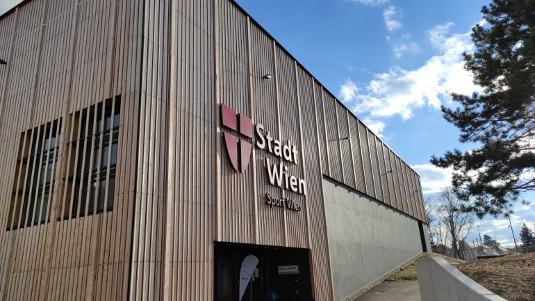 Sporthalle mit Holz-Fassade, mit Logo "Stadt Wien - Sport Wien"