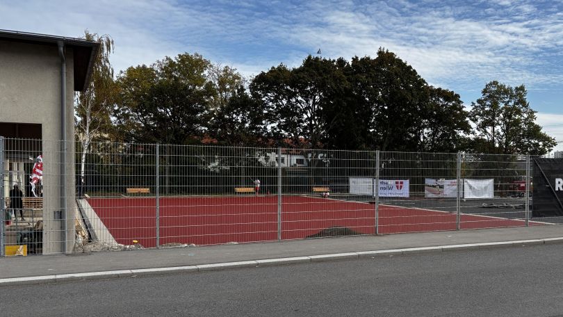 Sportplatz mit Gitter neben einer Straße.