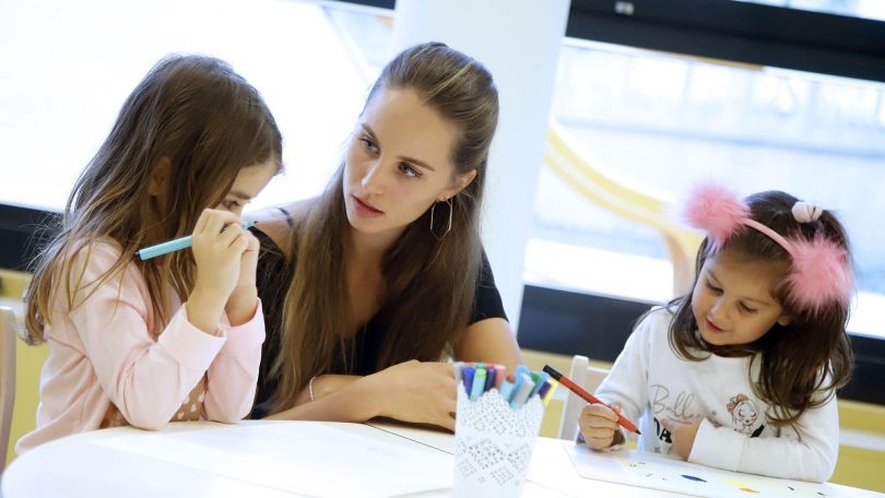 Elementarpädagogin mit zwei Mädchen beim Malen