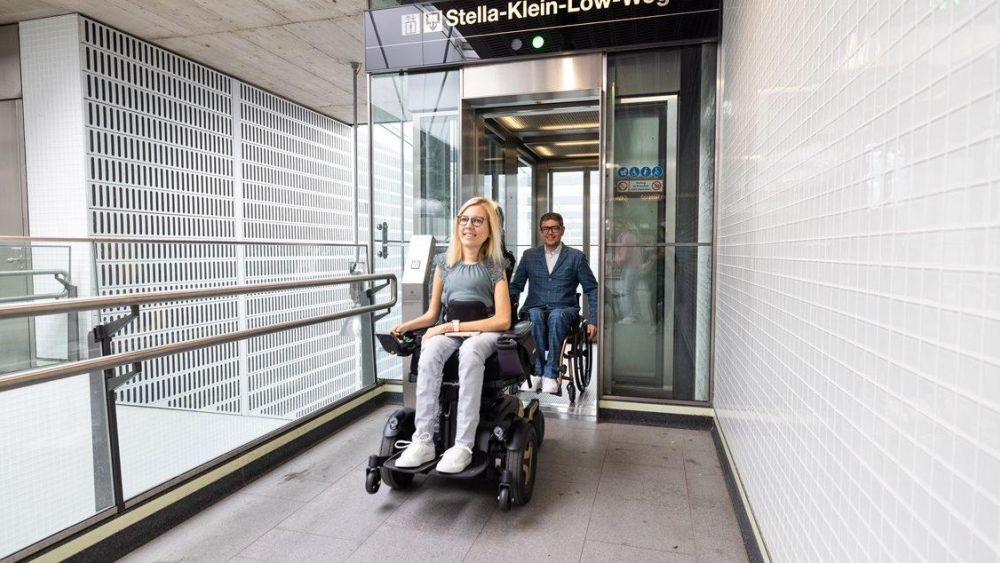 Eine Frau und ein Mann fahren im Rollstuhl aus einem Lift in einer U-Bahn-Station.