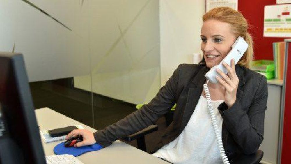 Eine Frau sitzt an einem Schreibtisch und telefoniert