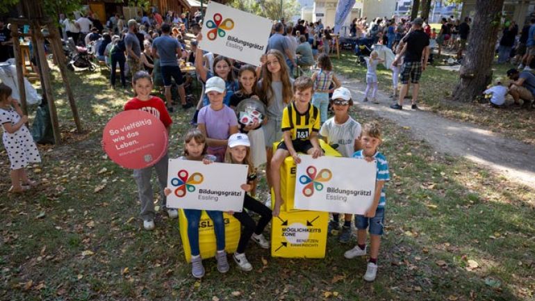 Kindergruppe hält Schilder mit "Bildungsgrätzl Essling"