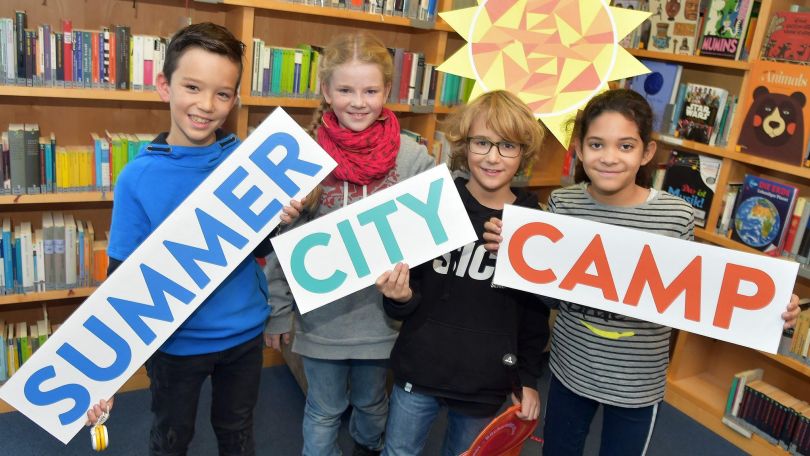 Kinder halten Schilder mit "Summer City Camp" hoch