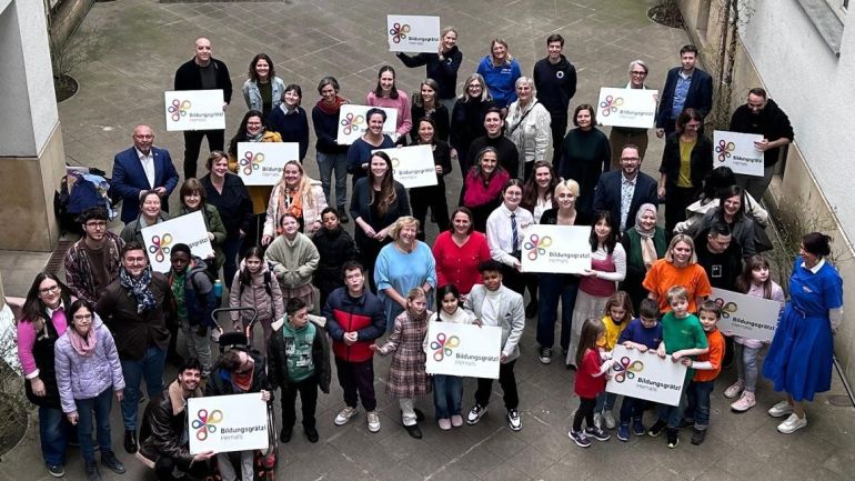 Kinder und Lehrpersonen halten Schild "Bildungsgrätzl Hernals" in die Höhe