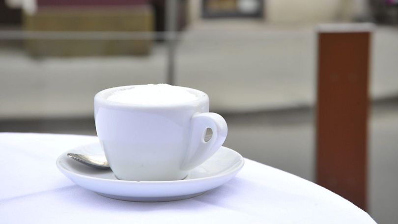 copyright: Alexandra Kromus / PID Eine weiße Kaffeetasse steht auf einem Tisch mit weißem Tischtuch.