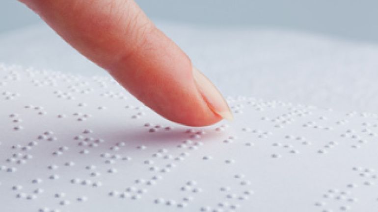 Ein Finger fährt über Braille-Schrift.