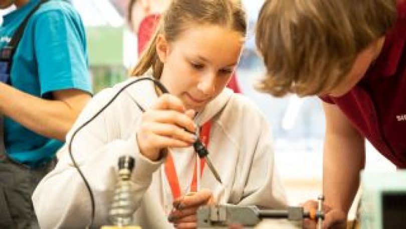 Mädchen lötet unter Anleitung mit Lötkolben