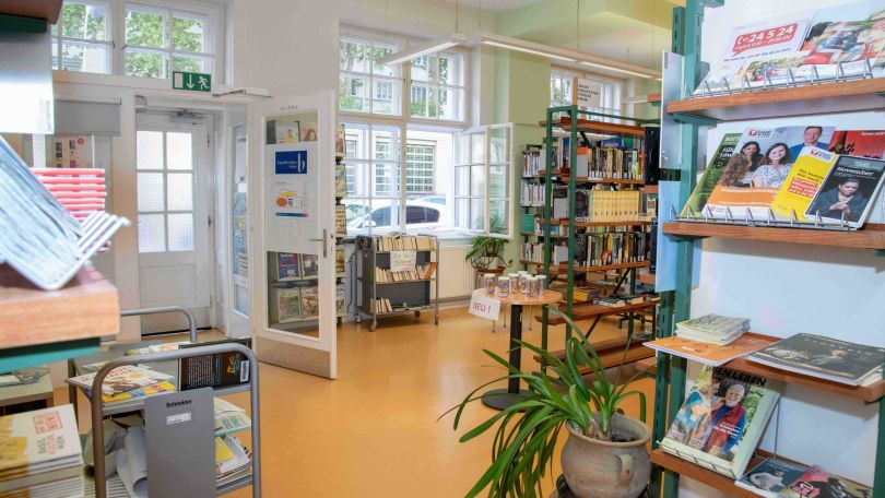 In einem hellen Altbau-Raum stehen Regale voller Zeitschriften und Bücher.