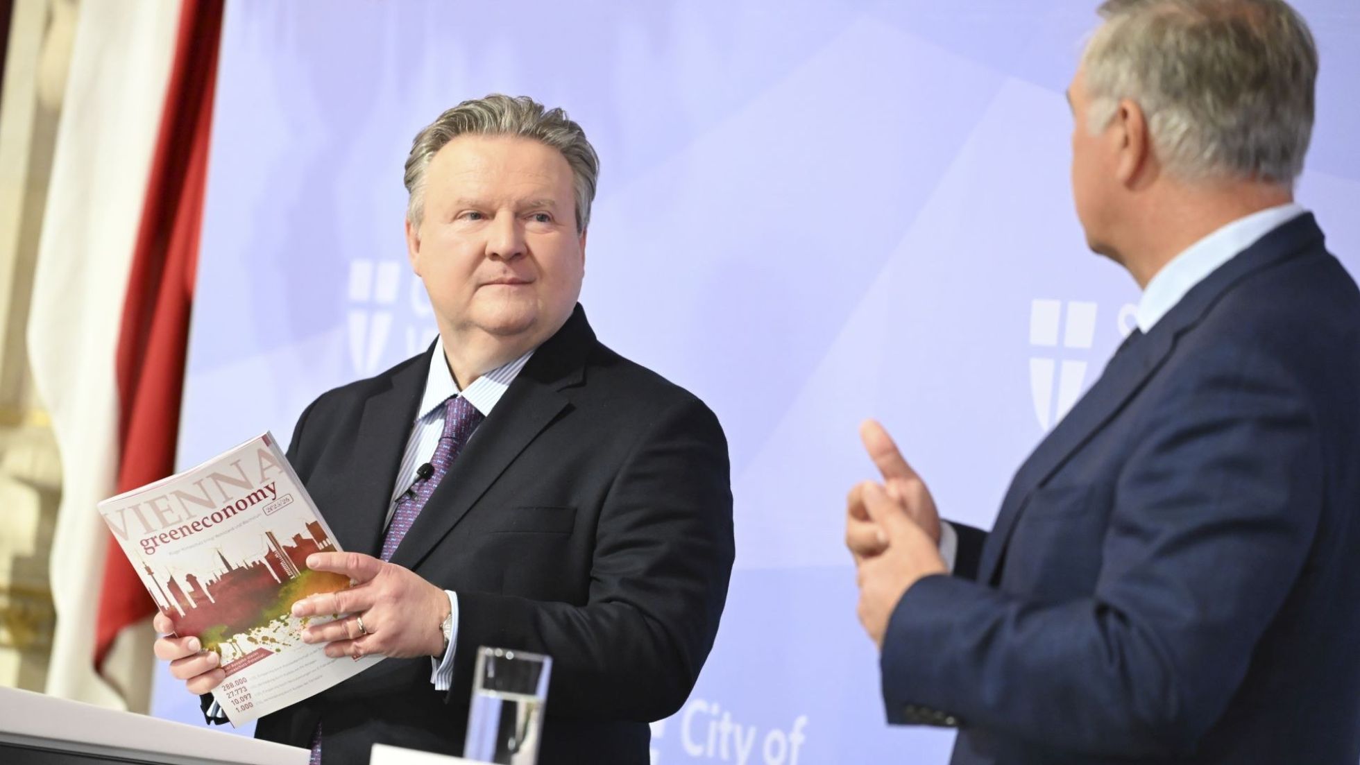 copyright: Stadt Wien / Christian Jobst Bürgermeister Michael Ludwig steht vor einem Redepult und hält eine Druckversion des Berichts in den Händen.