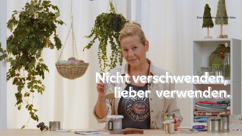 Eine Frau hält eine dekorierte Weißblechdose in der Hand. Vor ihr stehen weiter Dosen, manche sind bunt verziert.