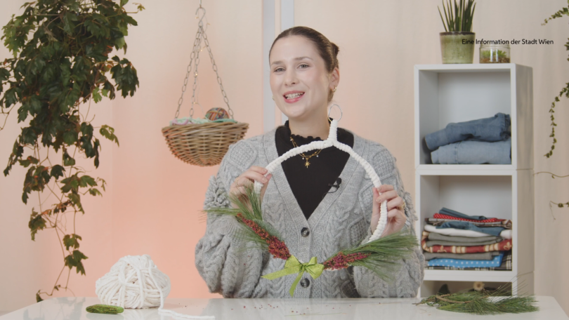 Eine Frau hält einen halbfertigen Türkranz in der Hand.