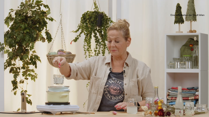 Eine Frau schmilzt Kerzenreste über einem Kochtopf.