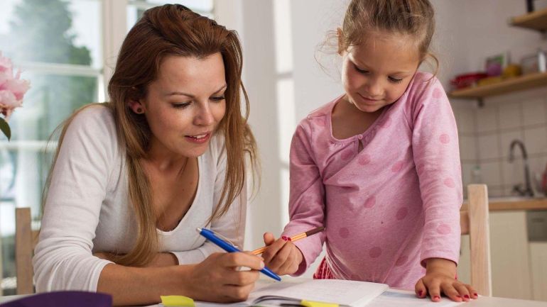 Frau und Mädchen beschäftigen sich mit einem Heft.