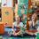 copyright: Stadt Wien Büchereien/Natalie Stephan 2 Kinder sitzen lachend auf dem Boden einer Bibliothek, während rund um sie zahlreiche bunte Sammelkarten durch die Luft fliegen. Im Hintergrund sind Bücherregale zu sehen.