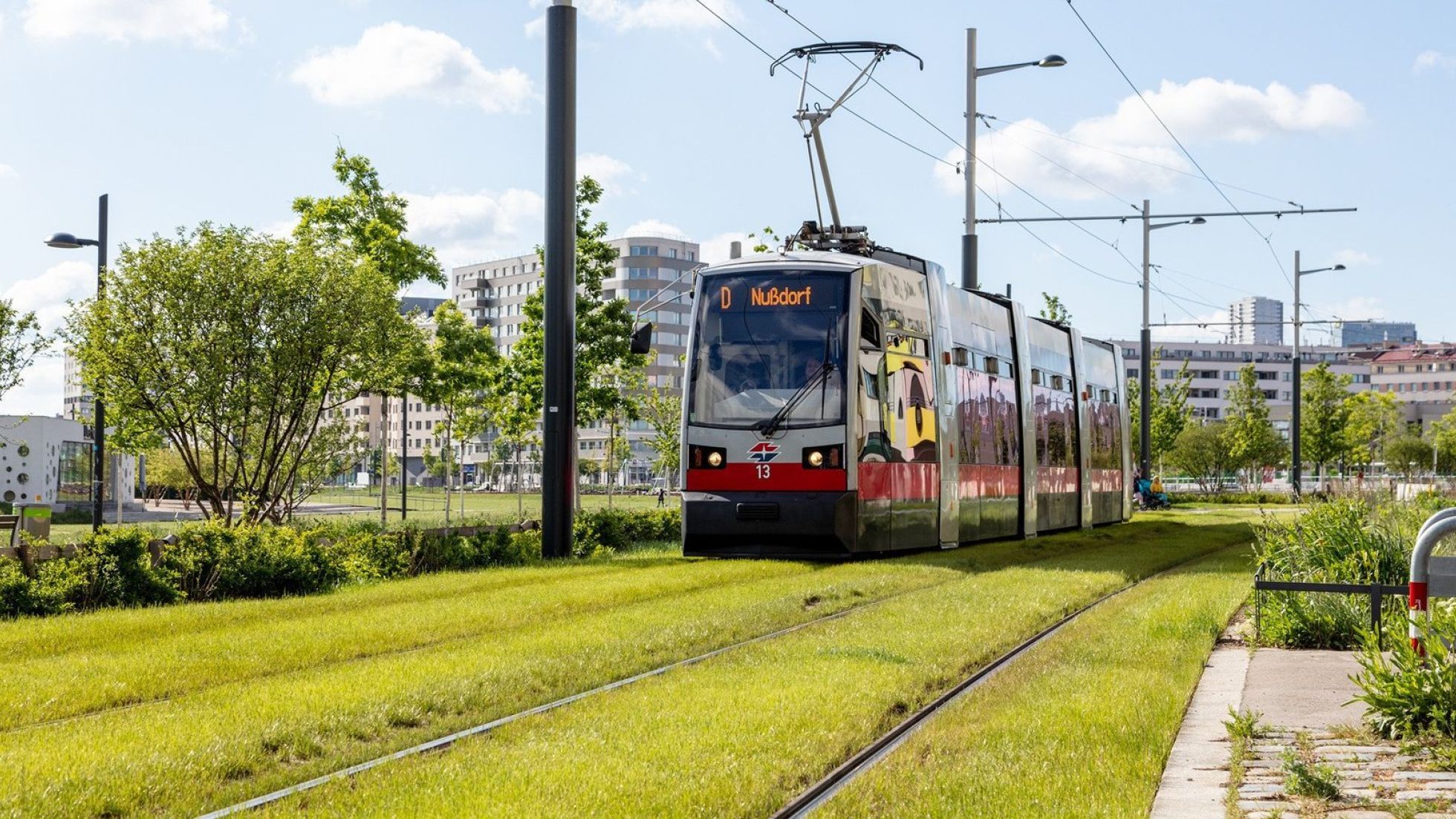 copyright: Wiener Linien - Helmer Eine Straßenbahn der Linie D fährt auf einem begrünten Gleis.