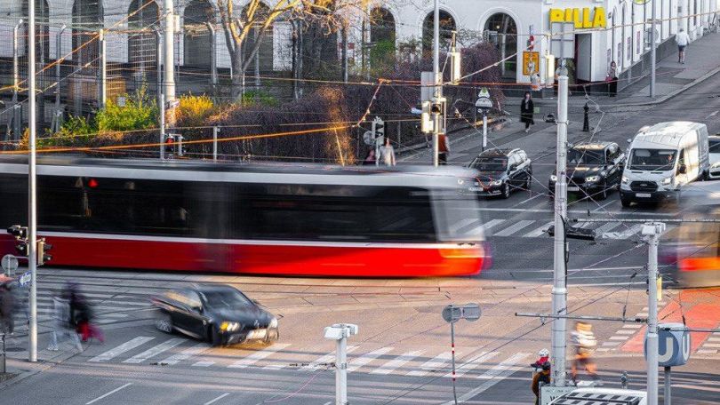 Eine Straßenbahn fährt über eine vielbefahrene Kreuzung.