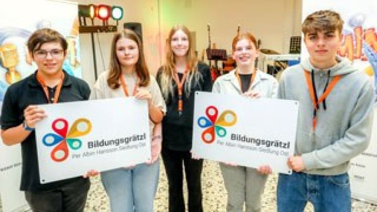 5 Jugendliche halten 2 Plakate "Bildungsgrätzl Per-Albin-Hansson-Siedlung Ost"