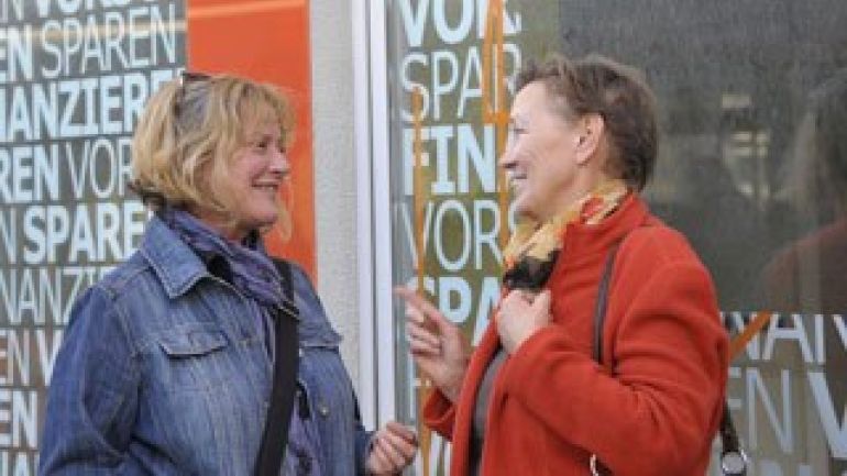 Zwei Frauen im Gespräch vor einem Sozialmarkt.