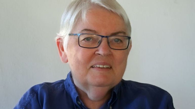 Frau mit kürzeren grauen Haaren, Brille und blauen Augen