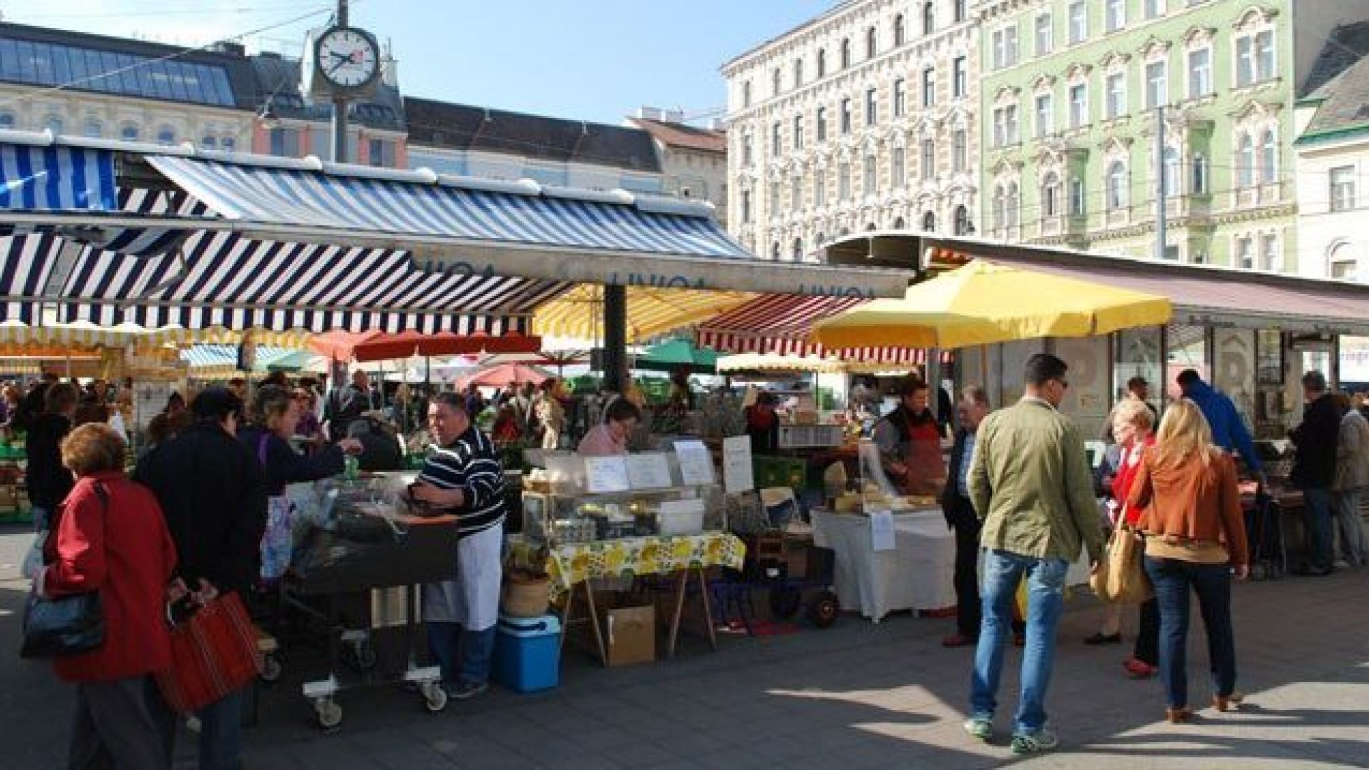 Stände auf einem Lebensmittelmarkt und Marktbesucher*innen