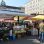 Stände auf einem Lebensmittelmarkt und Marktbesucher*innen