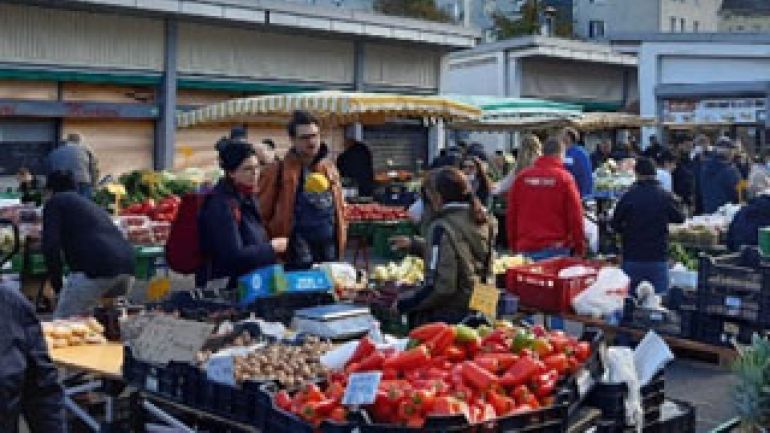 Menschen flanieren entlang von Marktständen