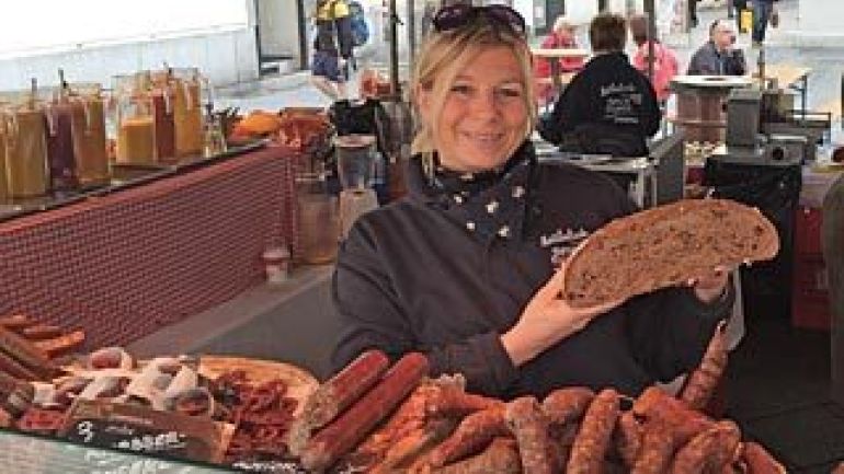 Verkäuferin eines Marktstandes mit einem halben Laib Brot