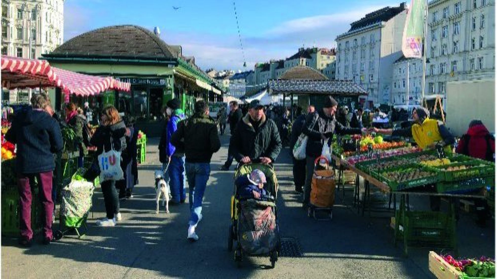 Personen gehen bei Obst- und Gemüseständen entlang