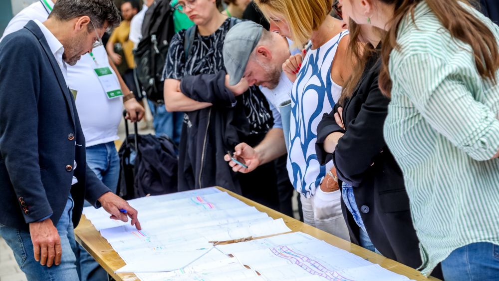 Mehrere Personen stehen rund um einen Tisch und betrachten Papiere.