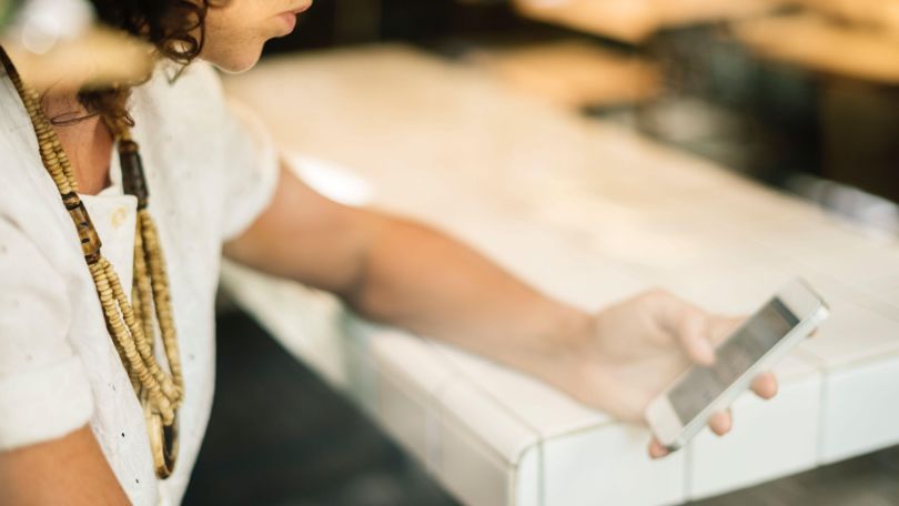 copyright: StockSnap/Pixabay Eine Frau sitzt an einem Tisch und betätigt ein Mobiltelefon