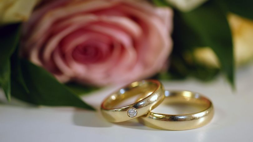 copyright: www.BilderBox.com Eheringe, dahinter eine Rose