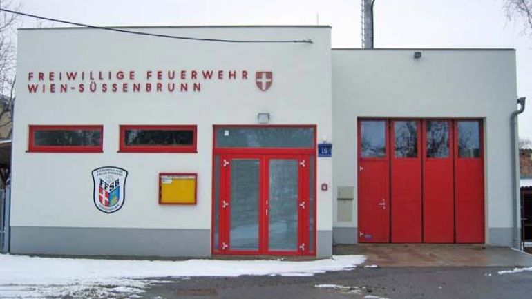 Frontalansicht der Freiwilligen Wache Süßenbrunn, ein abgesetzter Bau, Garagentor im Hintergrund, Tür im Vordergrund, zwei schmale Fenster